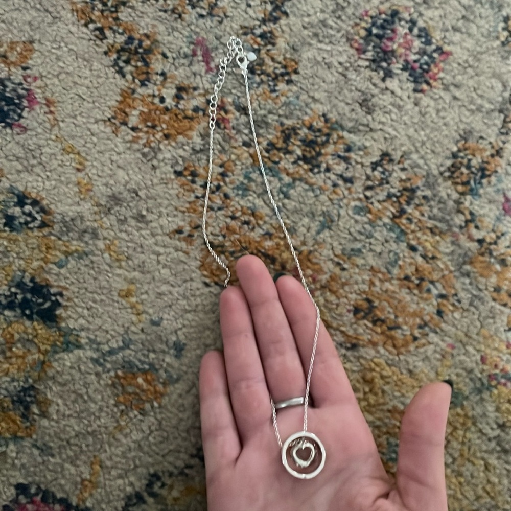 Silver necklace with a pink gem heart in the middle of the ring